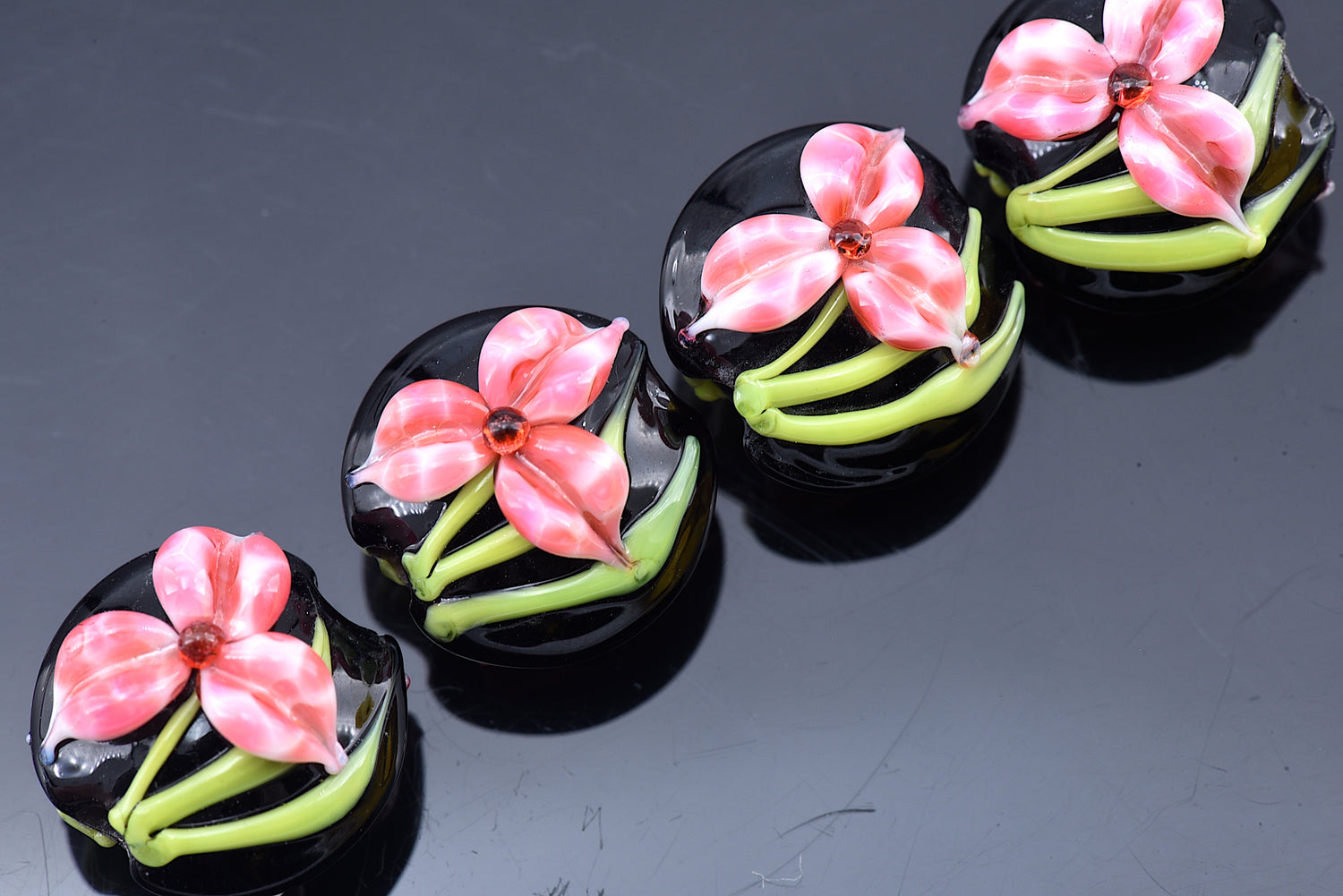 Black buttons with pink floral designs on a dark background