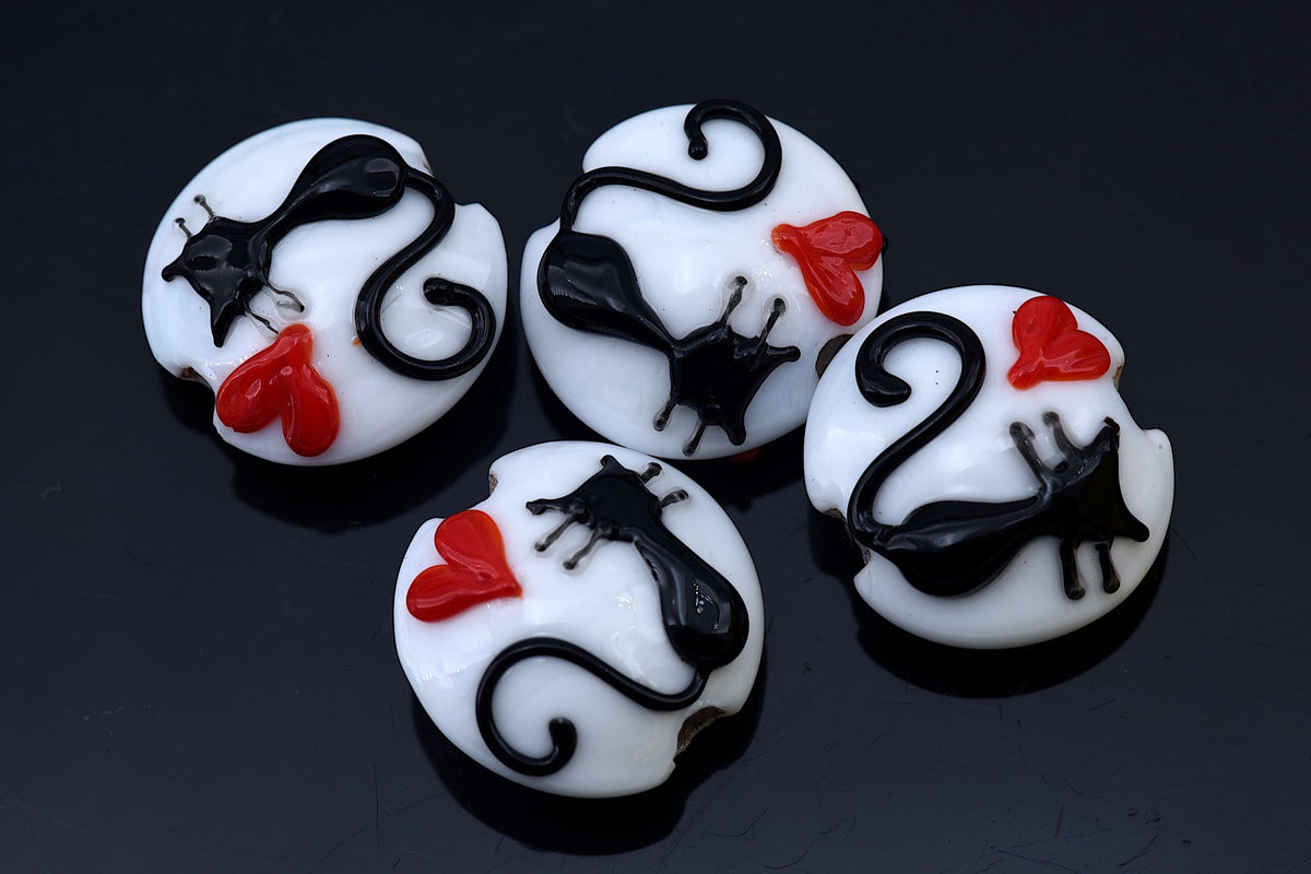 Four white buttons with black cat designs and red accents on a dark background