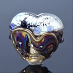 Heart-shaped glass object with multicolored design on a dark background