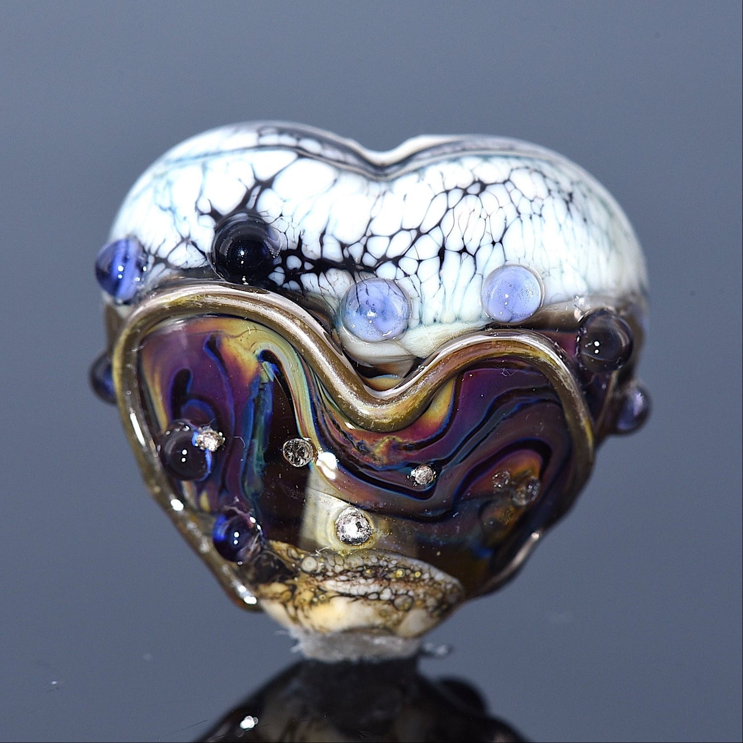 Heart-shaped glass object with multicolored design on a dark background