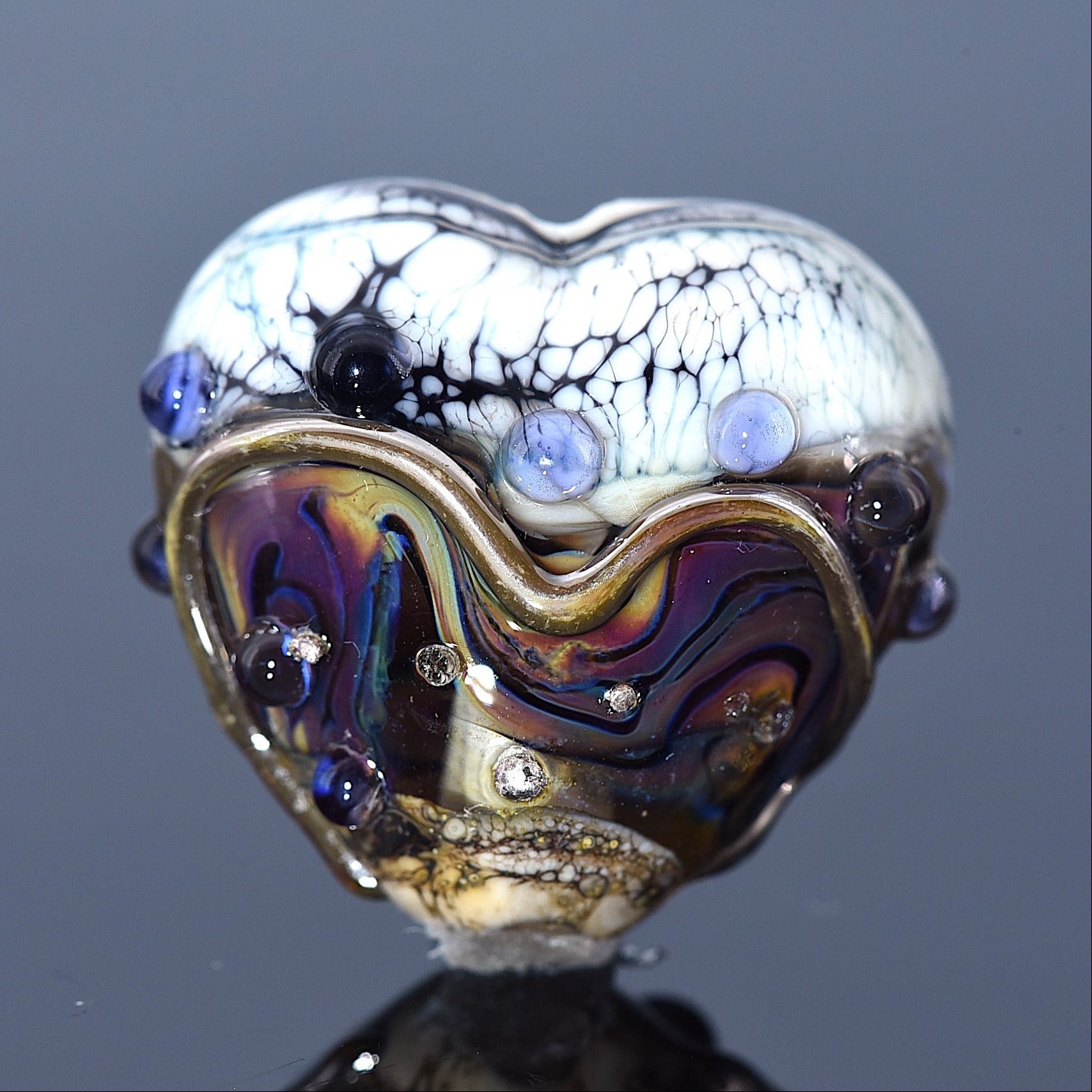 Heart-shaped glass object with multicolored design on a dark background