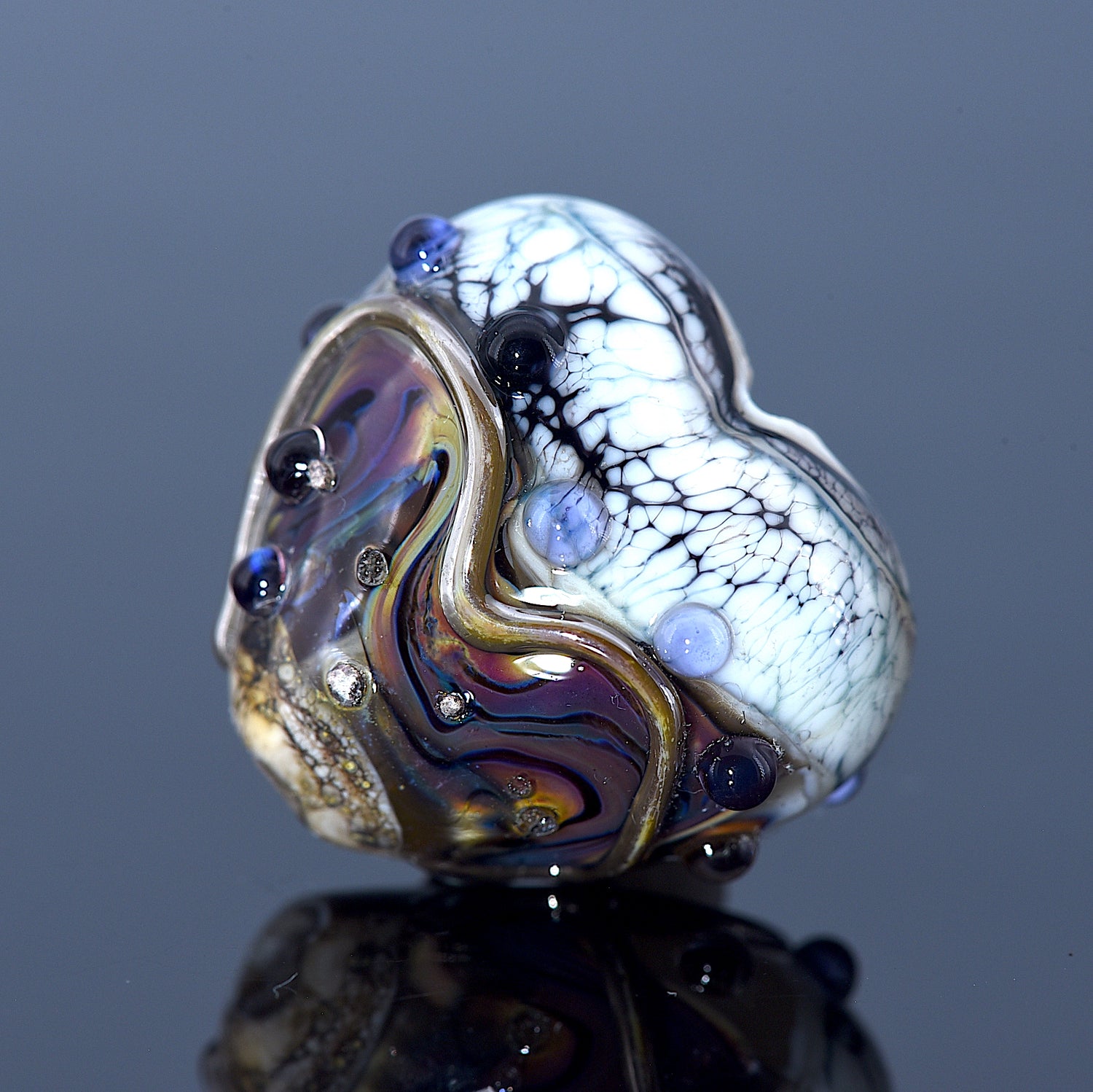 Glass bead with multicolored patterns on a reflective surface