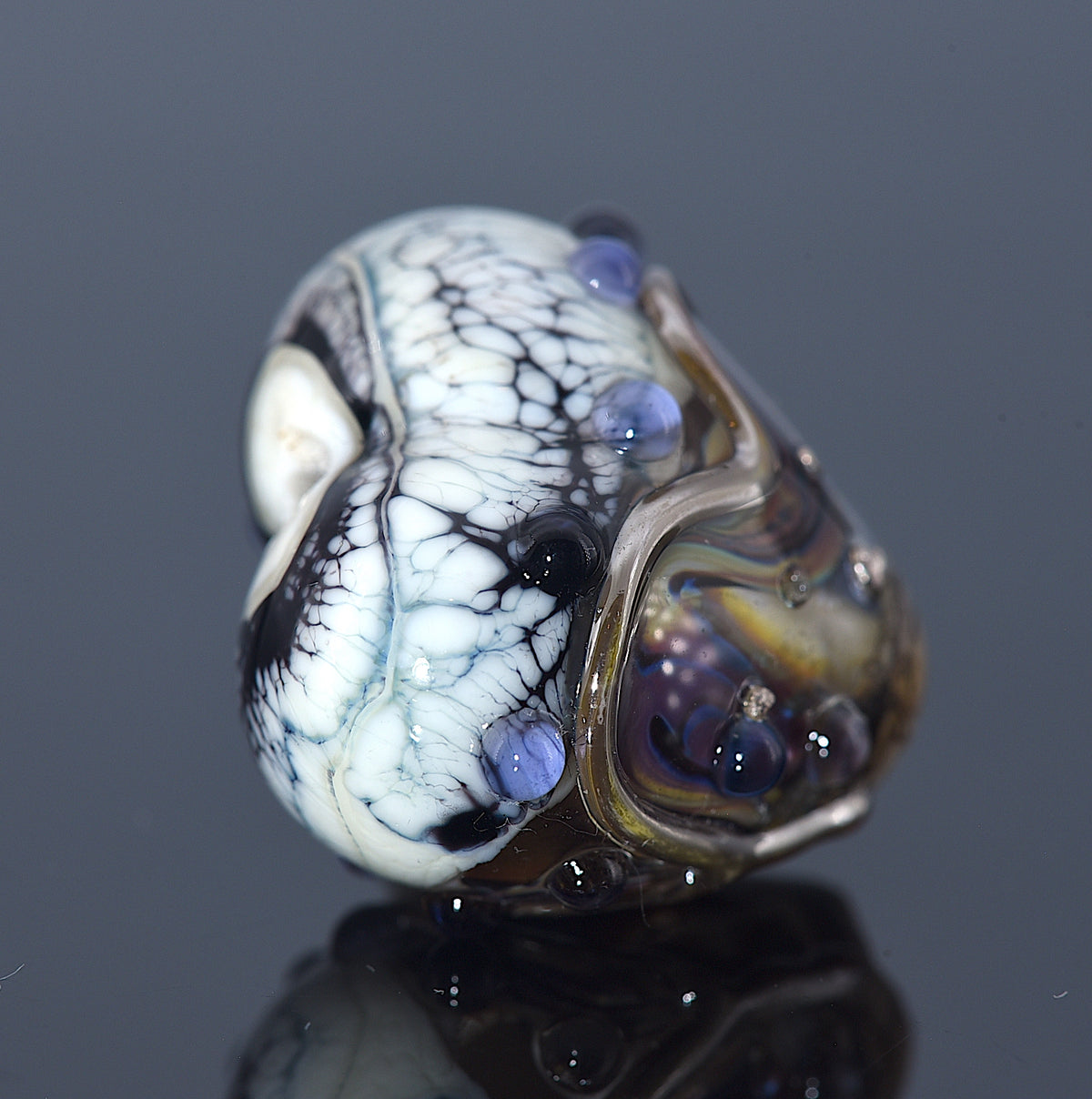 Glass bead with marbled pattern on a reflective surface