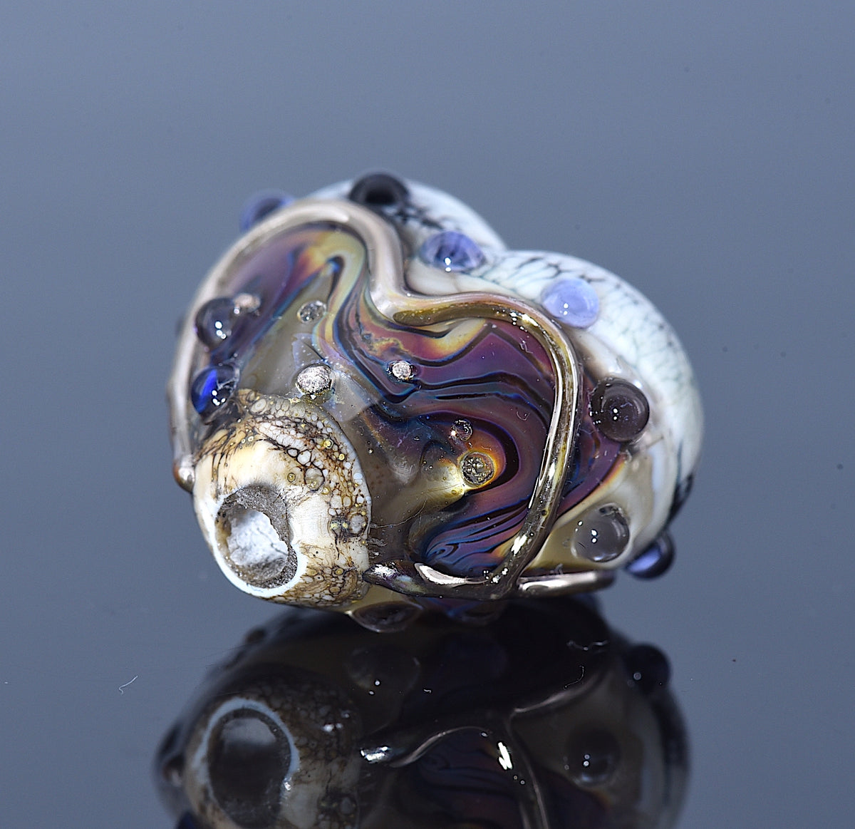 Close-up of a multicolored glass bead with a reflective surface on a dark background