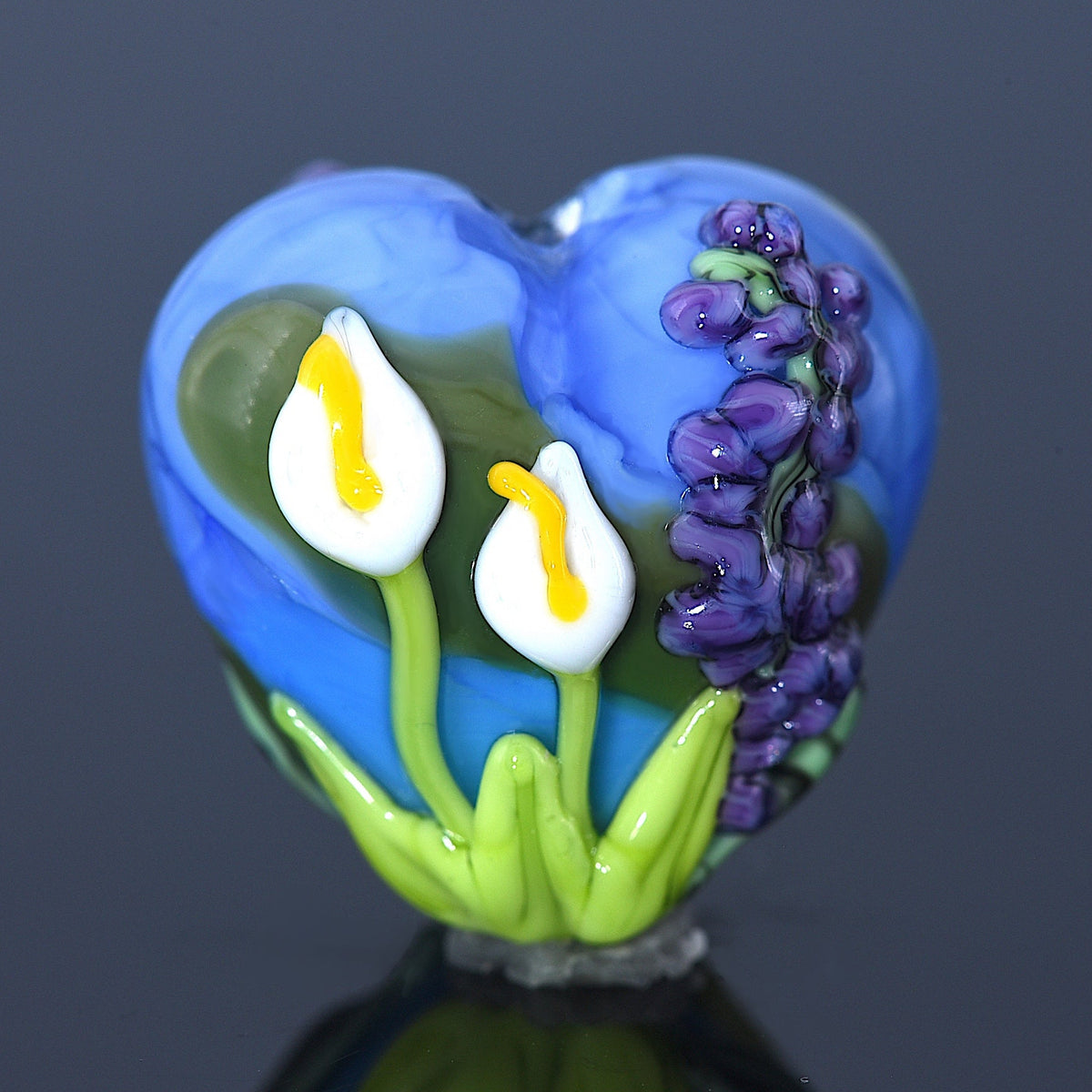 Heart-shaped glass ornament with flowers on a dark background