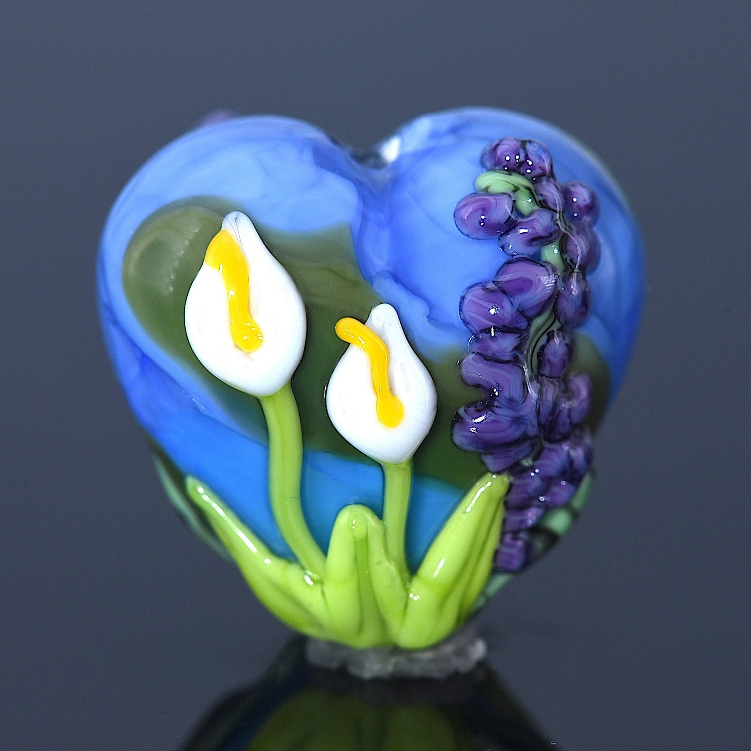 Heart-shaped glass ornament with flowers on a dark background