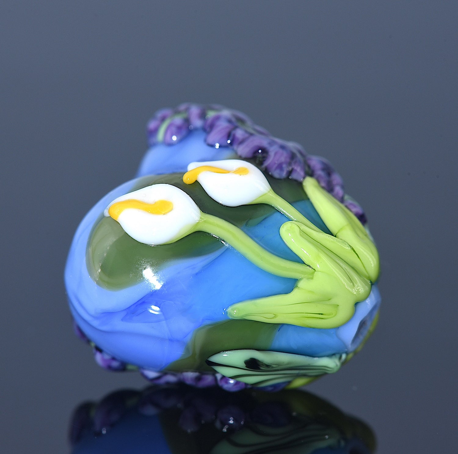 Colorful glass bead with floral design on a dark background