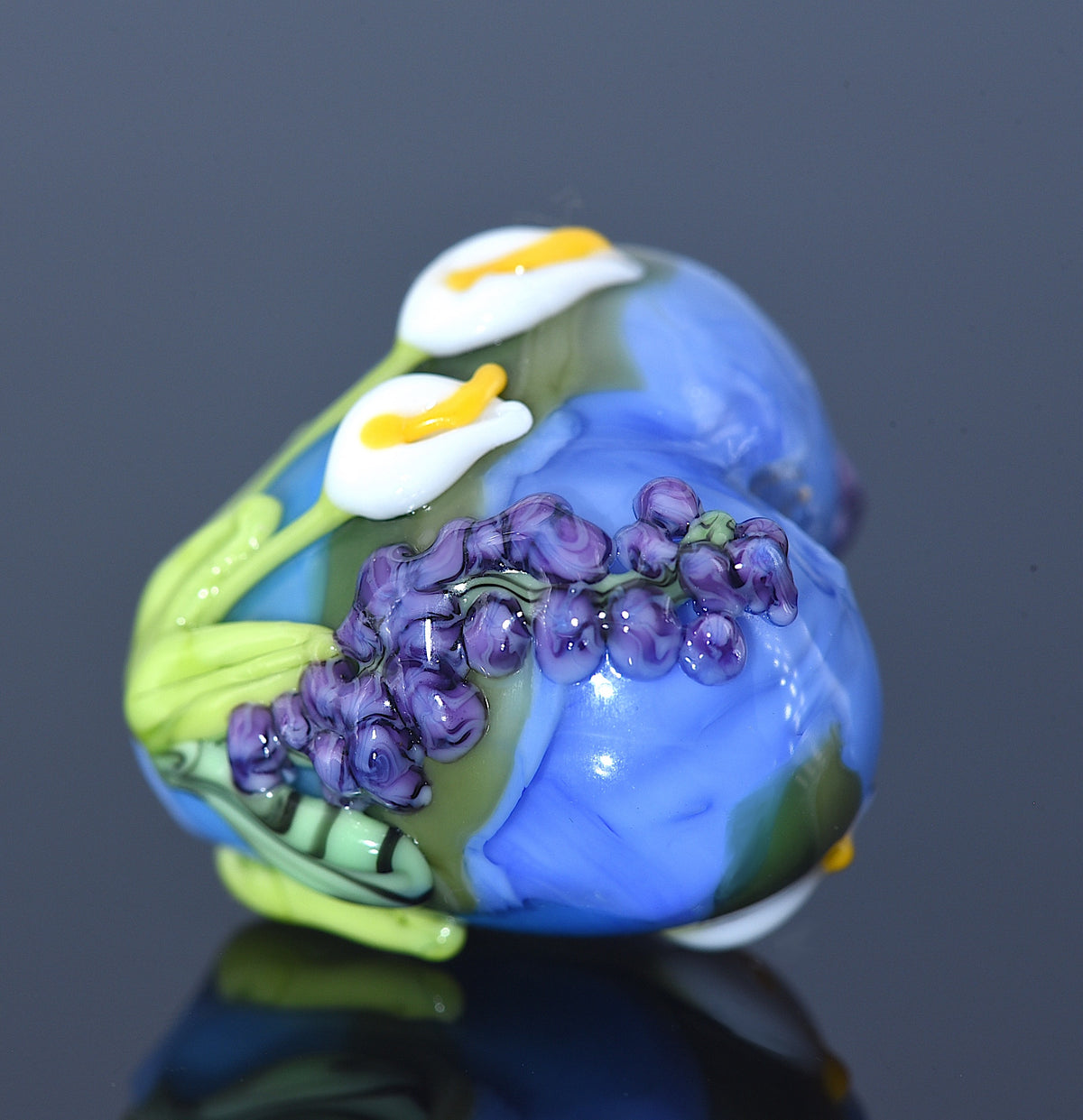 Glass sculpture of a flower with purple grapes on a dark background
