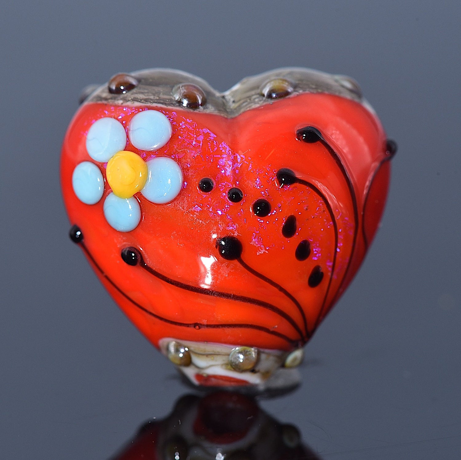 Heart-shaped object with floral design on a reflective surface