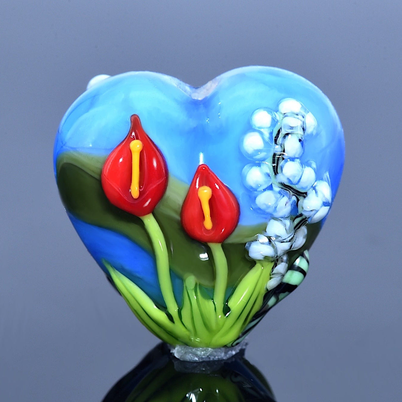 Heart-shaped glass sculpture with floral designs on a reflective surface