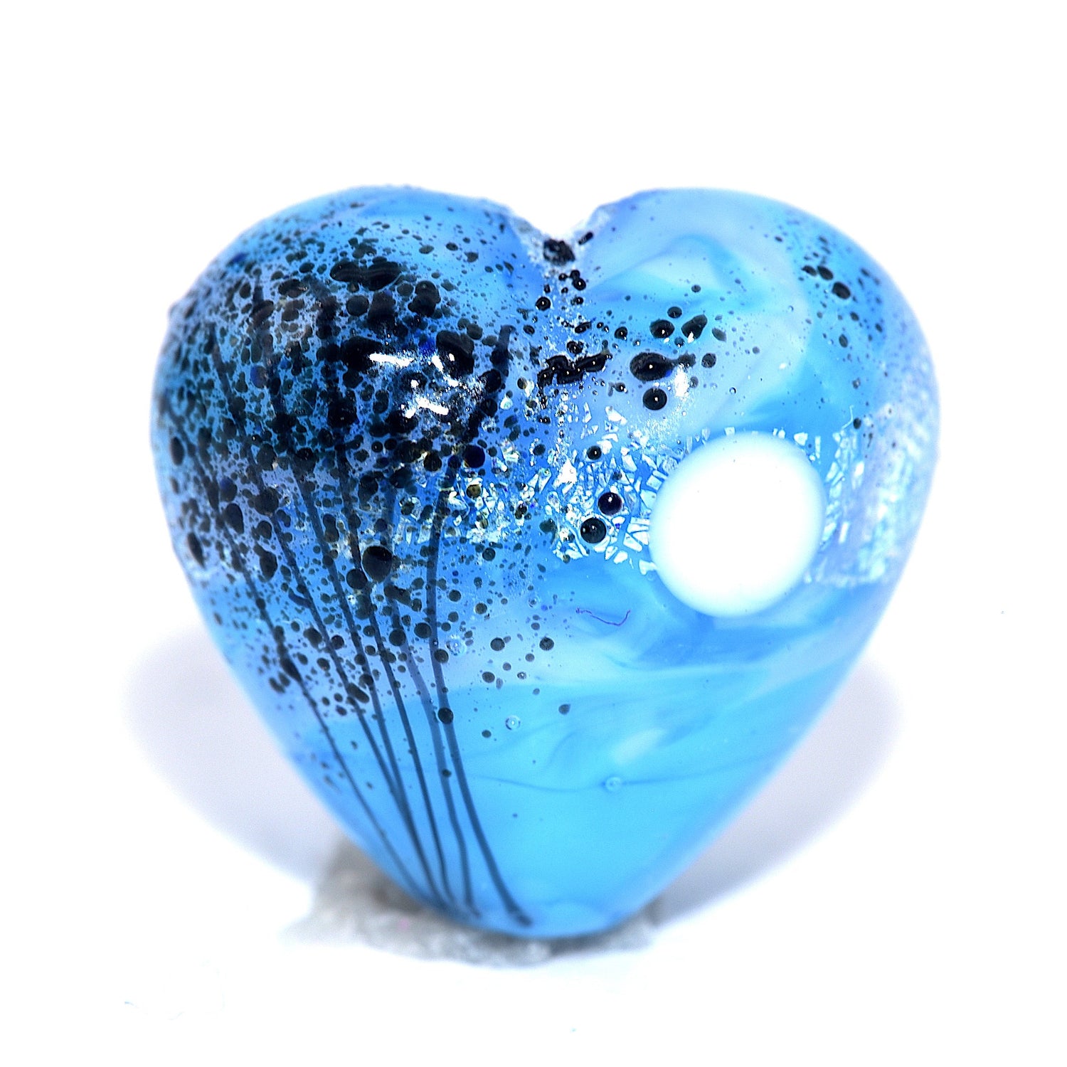 Blue heart-shaped object with black speckles on a white background