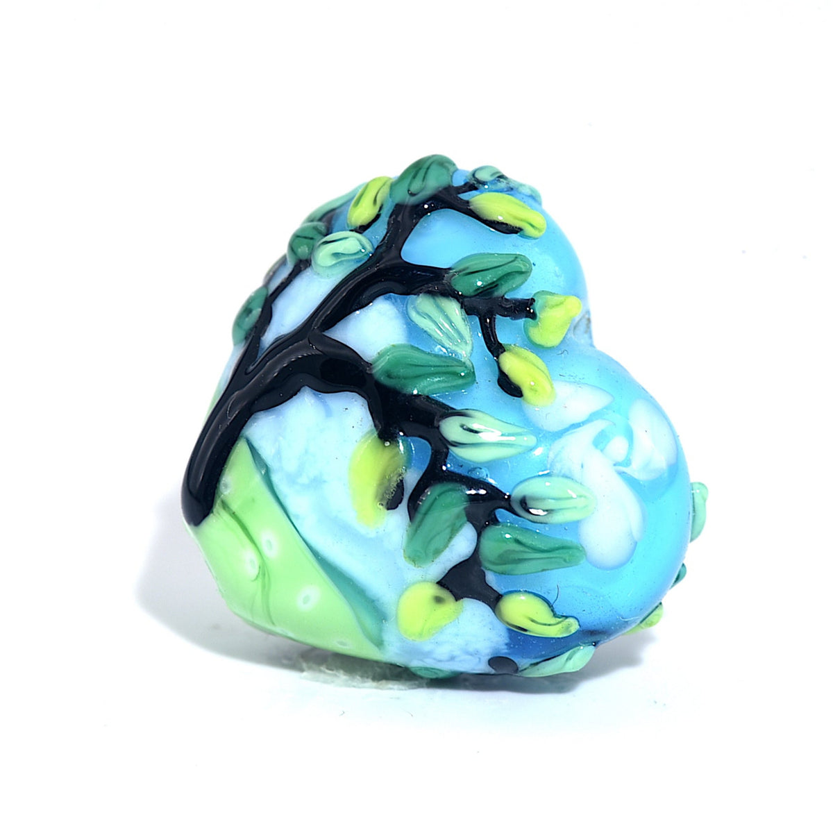 Decorative glass bead with tree design on a white background