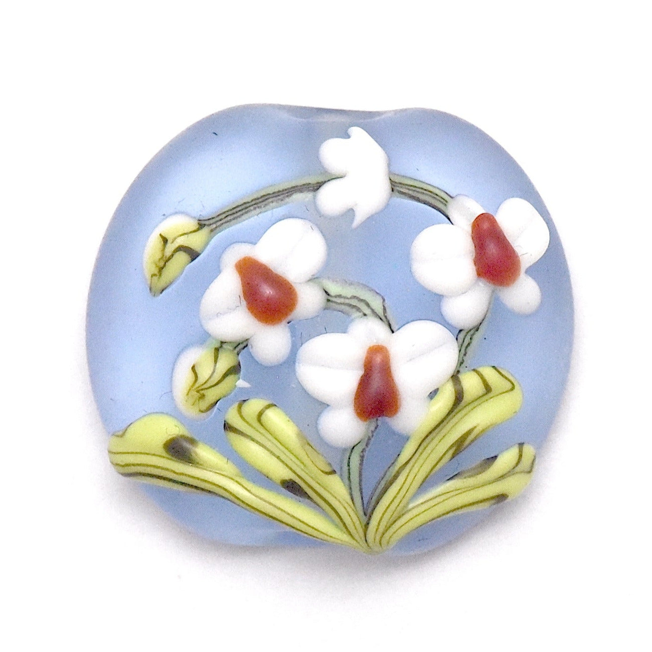 Decorative glass bead with floral design on a light blue background