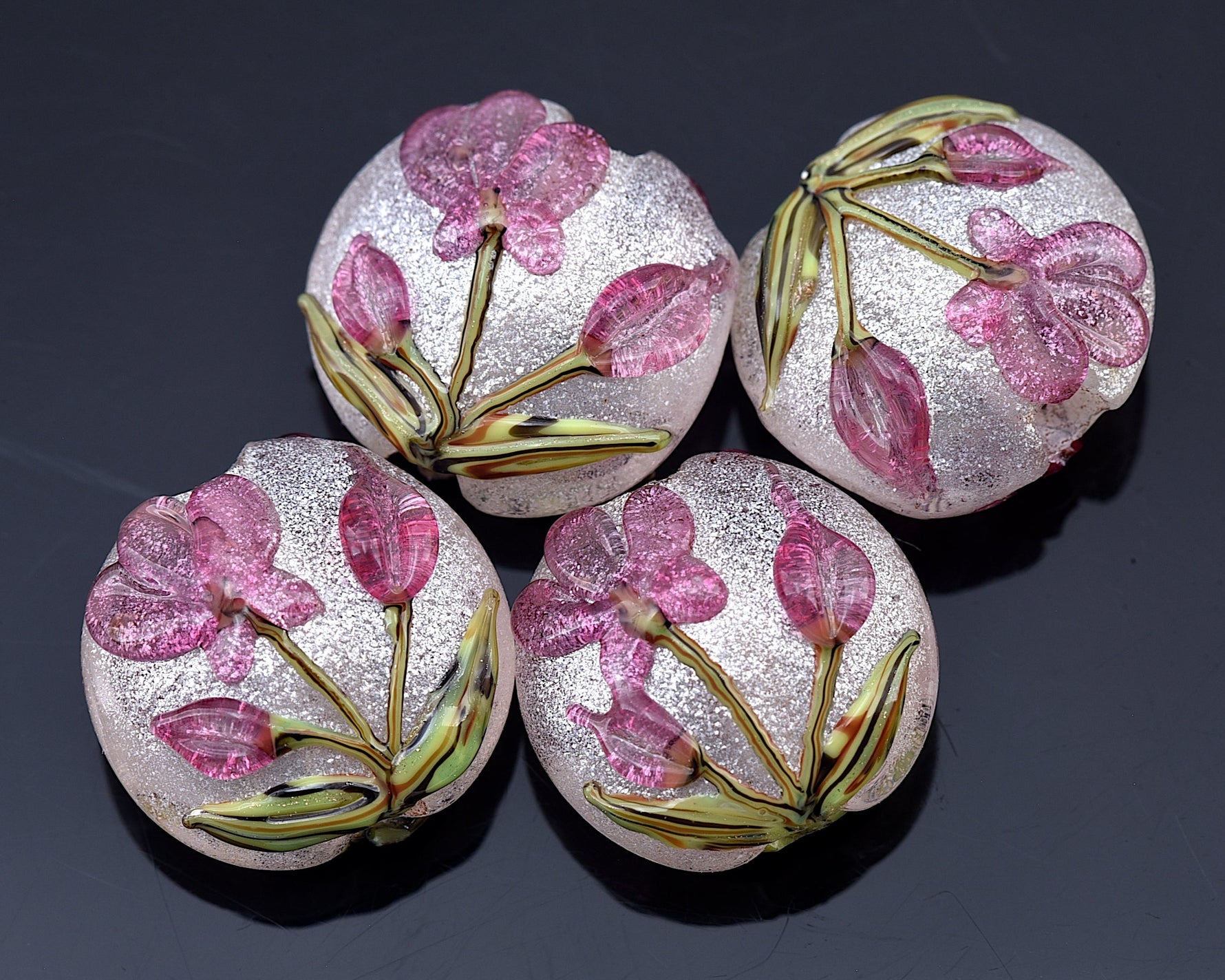 Four decorative buttons with floral design on a dark background