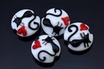 Four white buttons with black cat designs and red accents on a dark background
