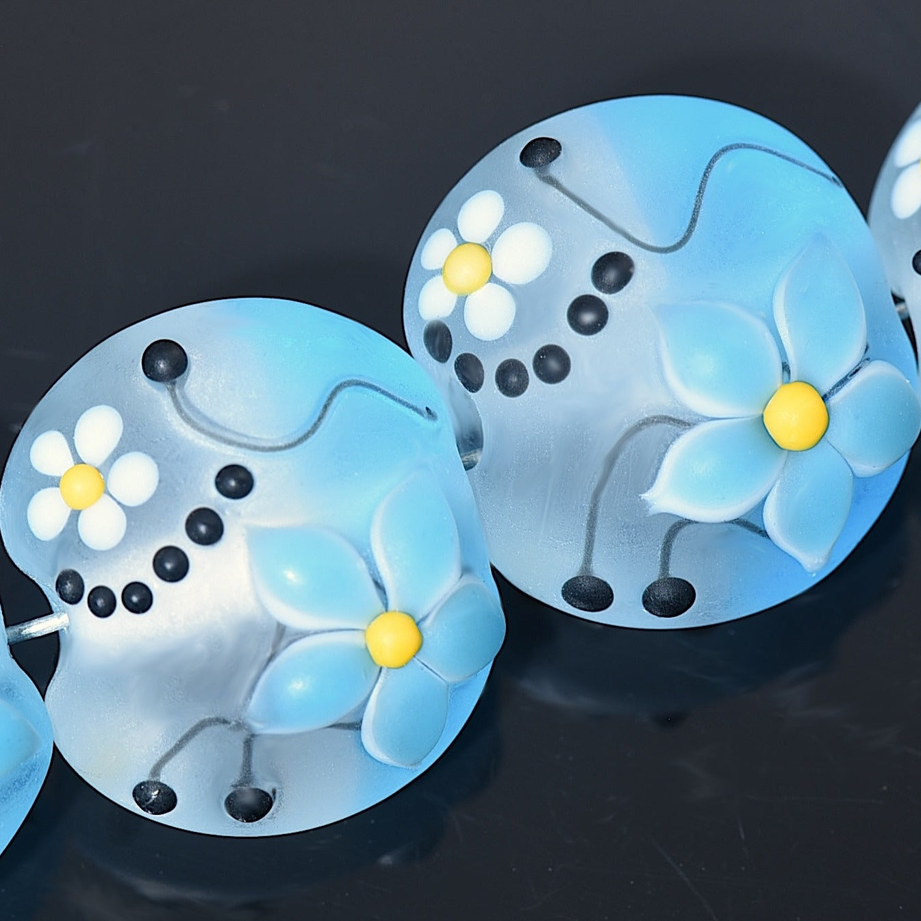 Blue flower-shaped objects with yellow centers on a dark background