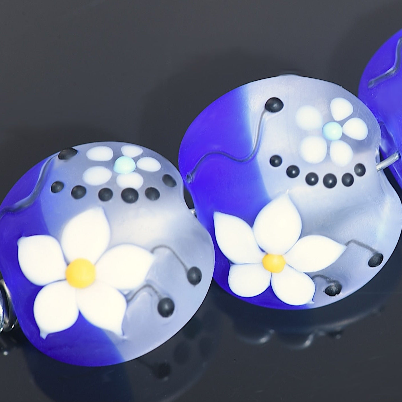 Two dental retainers with white flower designs on a dark background