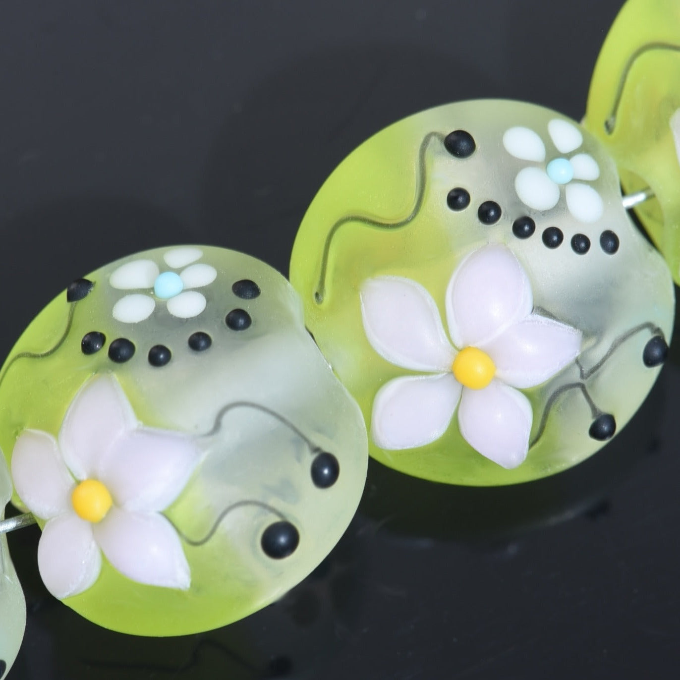 Decorative green buttons with floral designs on a black background