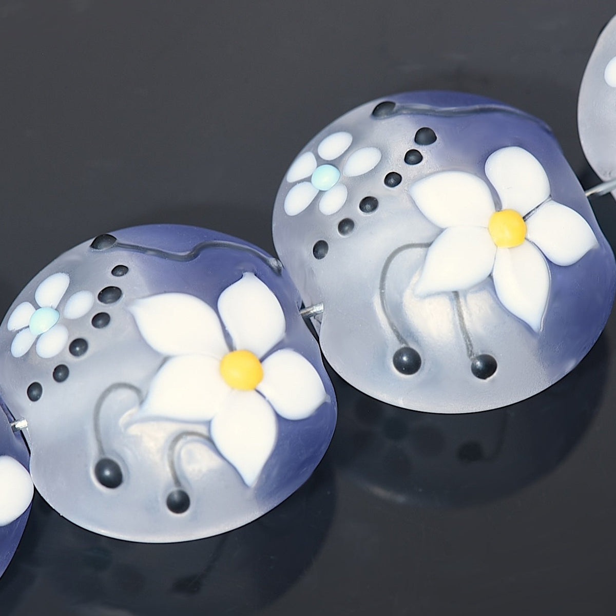 Transparent beads with white floral designs on a dark background