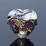 Heart-shaped glass bead with multicolored design and embedded stones on a dark background