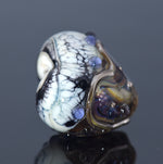 Glass bead with marbled pattern on a reflective surface