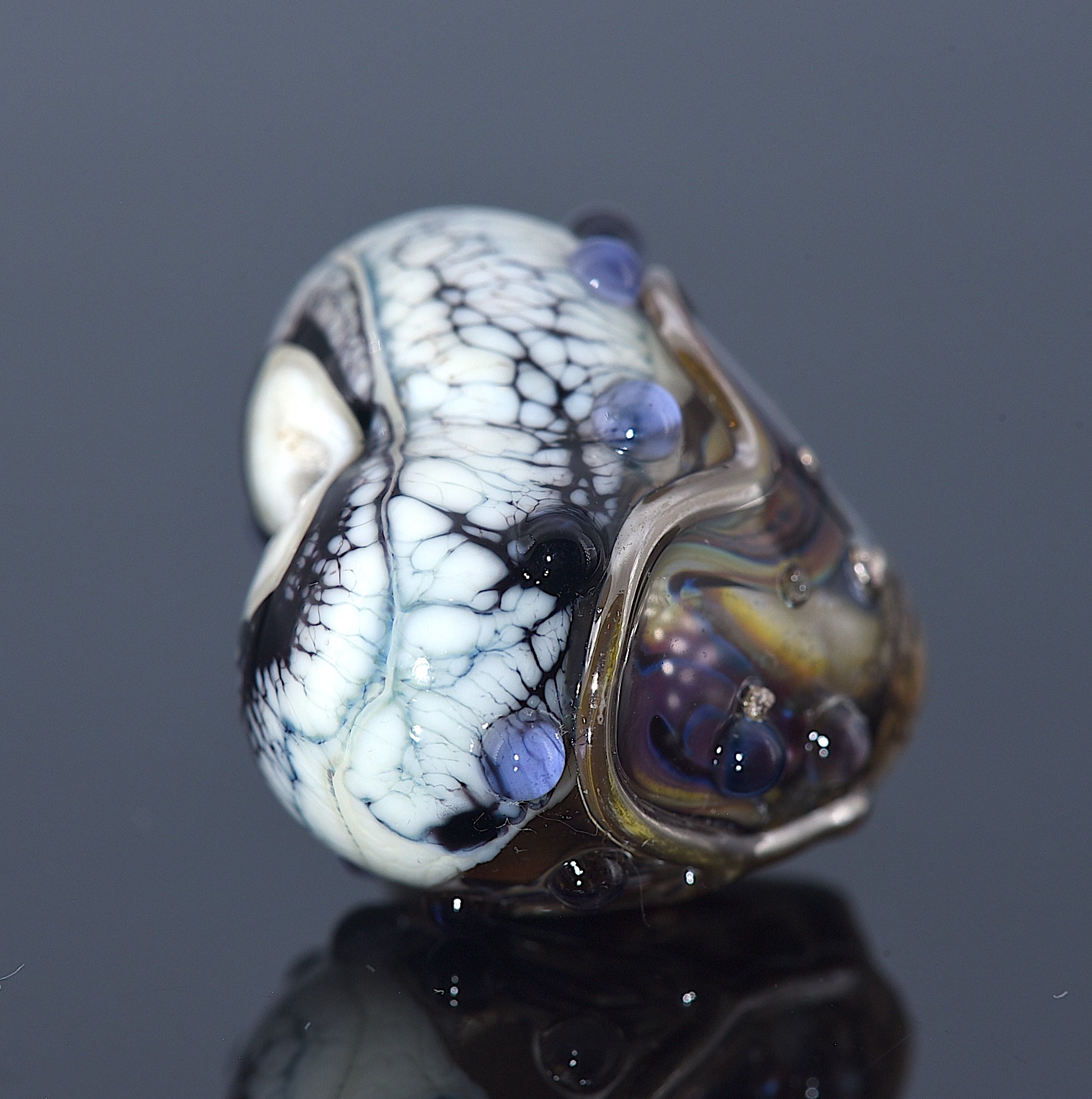 Glass bead with marbled pattern on a reflective surface