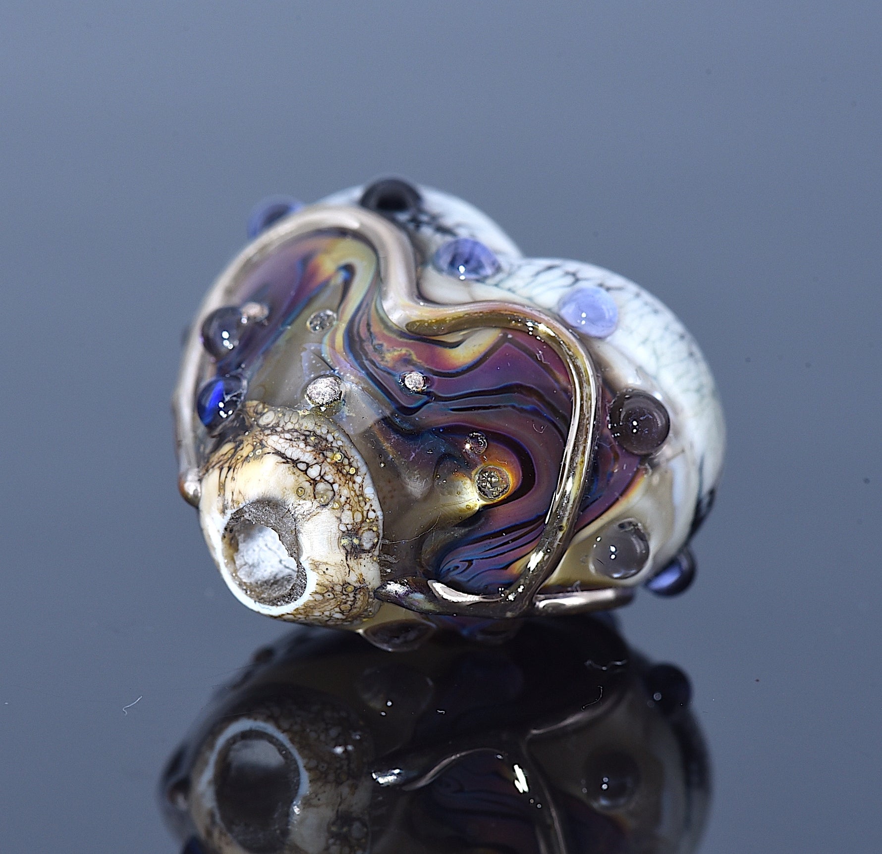 Close-up of a multicolored glass bead with a reflective surface on a dark background