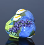 Glass sculpture of a flower with purple grapes on a dark background