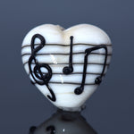 Heart-shaped object with musical notes on a reflective surface