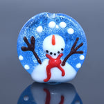 Glass snow globe with a small snowman figure inside on a reflective surface.
