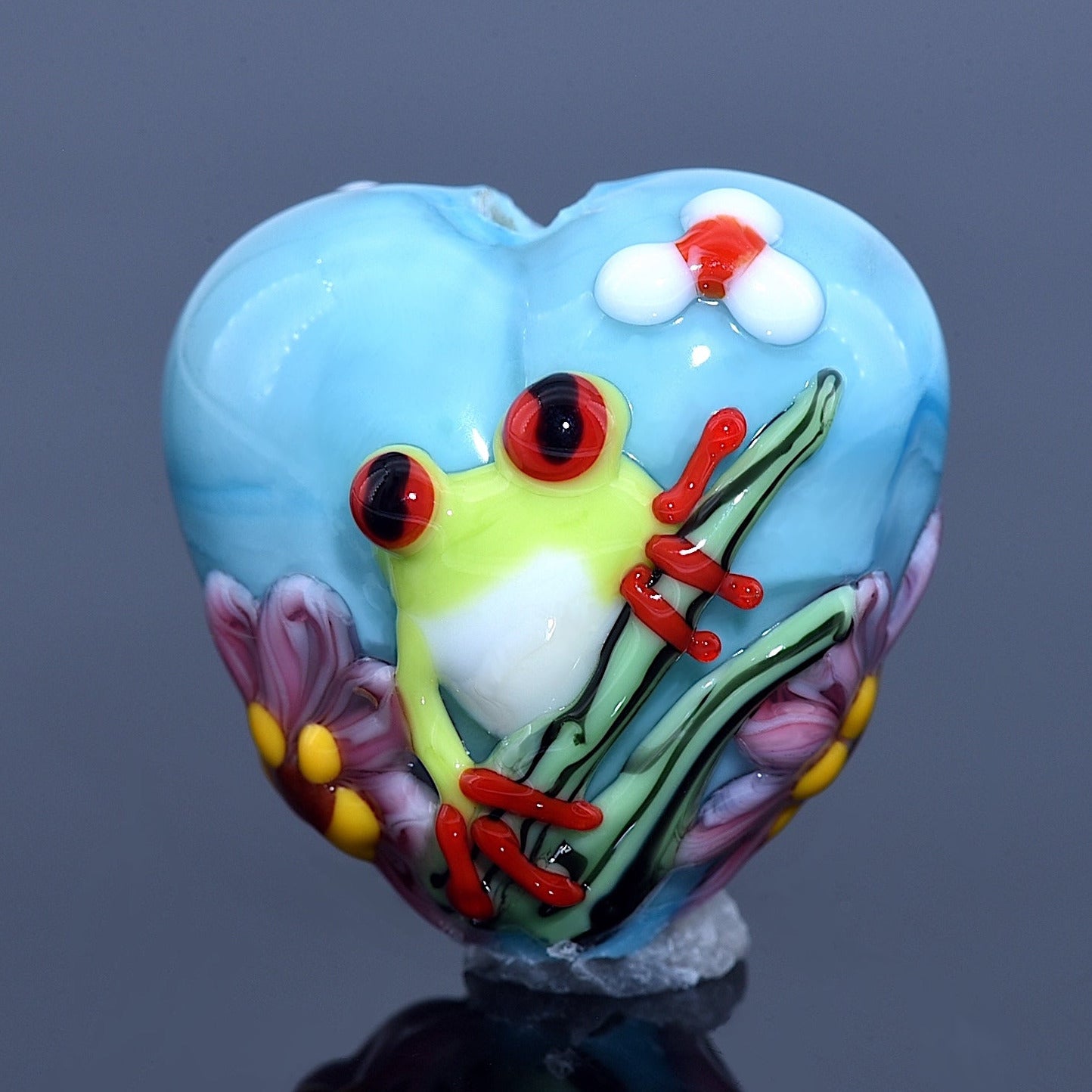Heart-shaped object with a frog design on a blue background