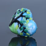 Decorative glass bead with tree design on a reflective surface