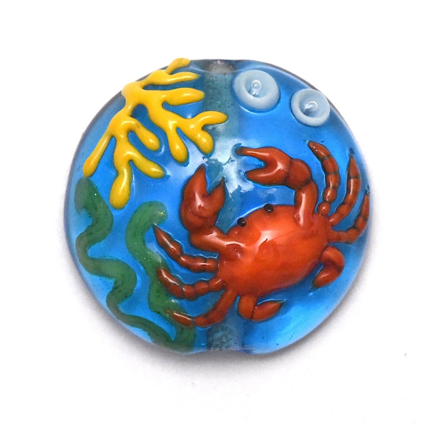 Decorative glass piece with a red crab, yellow coral, and blue water background.