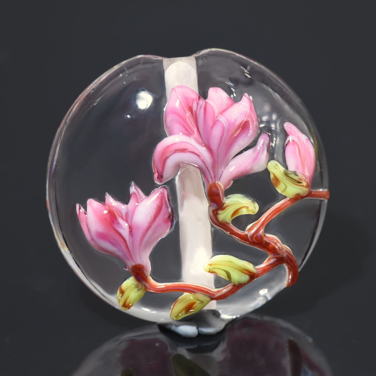 Glass object with pink floral design on a dark background